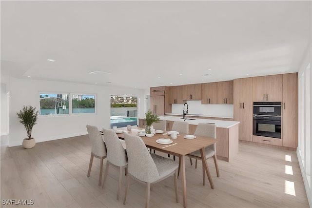 dining space with sink and light wood-type flooring