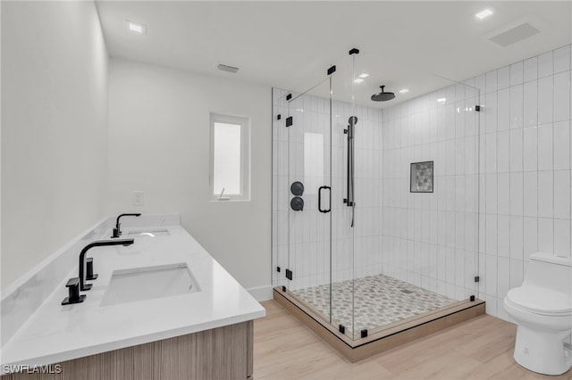 bathroom featuring hardwood / wood-style flooring, a shower with shower door, vanity, and toilet