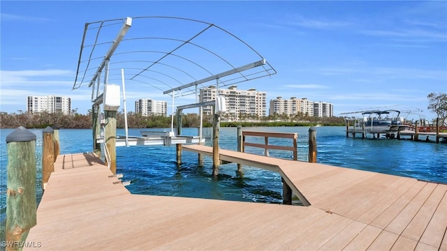 view of dock with a city view, a water view, and boat lift