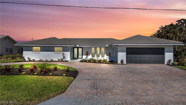 single story home featuring decorative driveway, a tile roof, an attached garage, and stucco siding