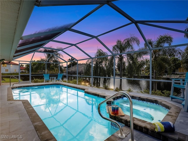 pool at dusk featuring a lanai, a water view, an in ground hot tub, and a patio