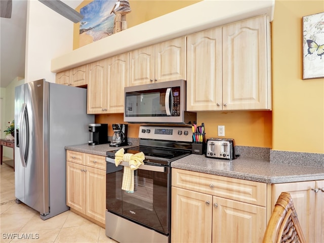 kitchen featuring stainless steel appliances, light brown cabinetry, and light tile patterned flooring