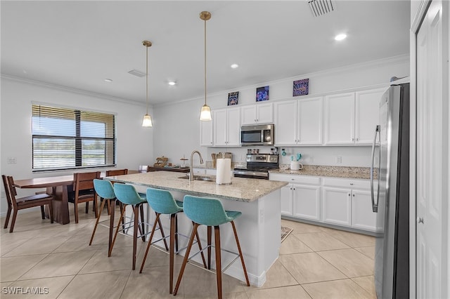 kitchen featuring light stone countertops, appliances with stainless steel finishes, pendant lighting, and white cabinetry