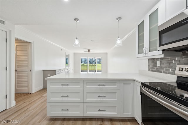 kitchen with appliances with stainless steel finishes, backsplash, white cabinetry, light hardwood / wood-style floors, and decorative light fixtures