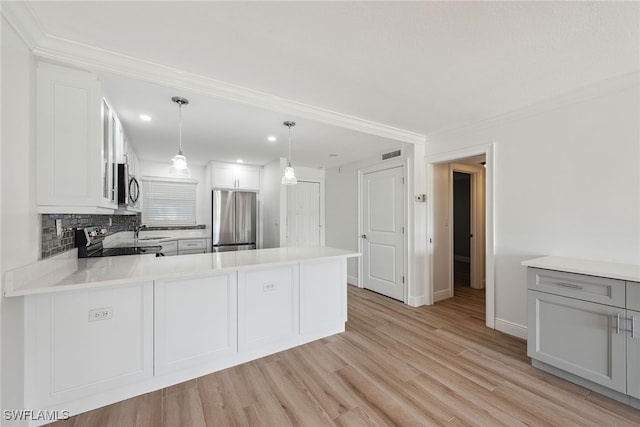 kitchen featuring appliances with stainless steel finishes, kitchen peninsula, decorative light fixtures, and light wood-type flooring