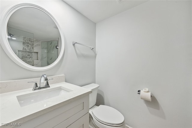 bathroom featuring toilet, a shower with shower door, and vanity