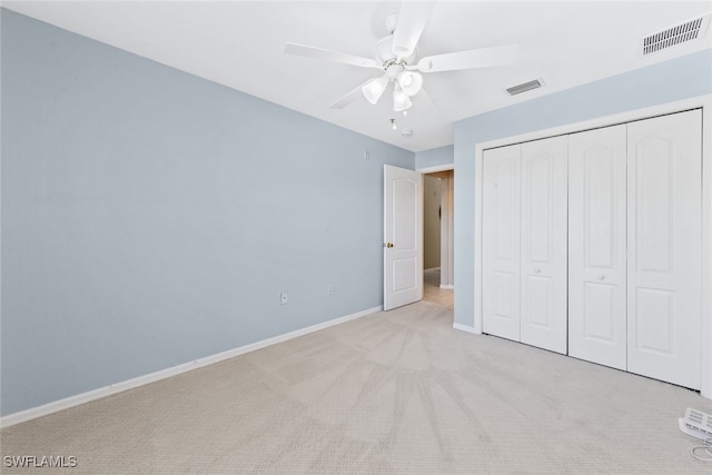 unfurnished bedroom featuring ceiling fan, light colored carpet, and a closet