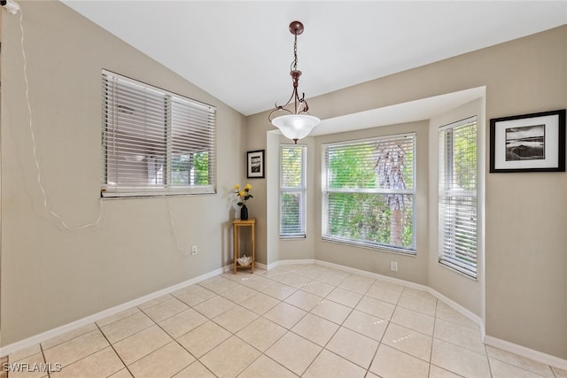 tiled spare room featuring vaulted ceiling