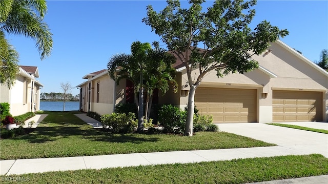 view of front of house featuring a front yard, a garage, and a water view