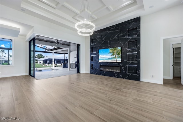 unfurnished living room featuring light hardwood / wood-style floors, a chandelier, coffered ceiling, and beamed ceiling