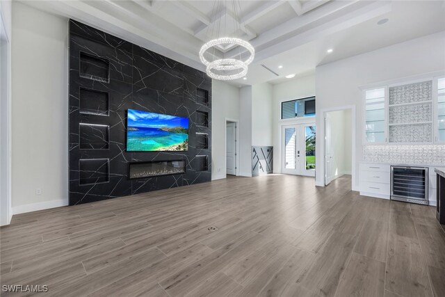 unfurnished living room with french doors, hardwood / wood-style floors, coffered ceiling, beamed ceiling, and wine cooler