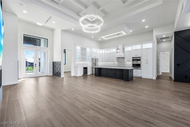 kitchen featuring white cabinets, dark hardwood / wood-style floors, a center island with sink, and hanging light fixtures