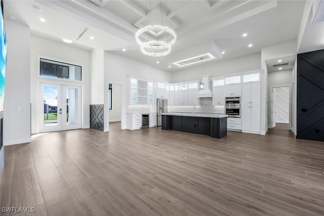 kitchen with open floor plan, white cabinets, a center island with sink, and decorative light fixtures