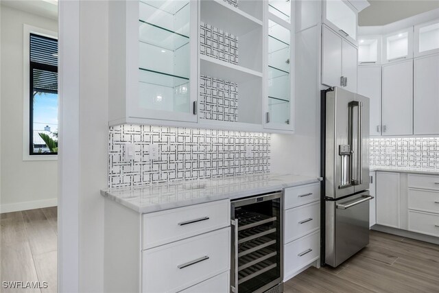 kitchen with wine cooler, white cabinets, tasteful backsplash, light hardwood / wood-style flooring, and high end fridge