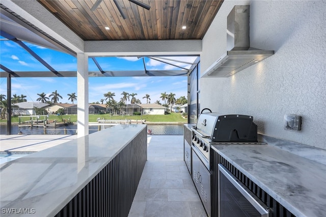 view of patio featuring exterior kitchen, a residential view, a water view, and grilling area