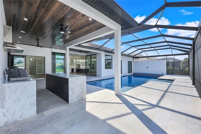 pool featuring ceiling fan, a patio, glass enclosure, outdoor wet bar, and area for grilling