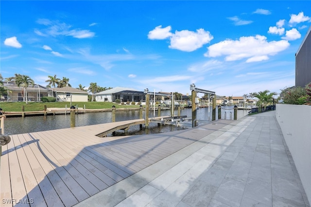 dock area with a water view, boat lift, and a residential view