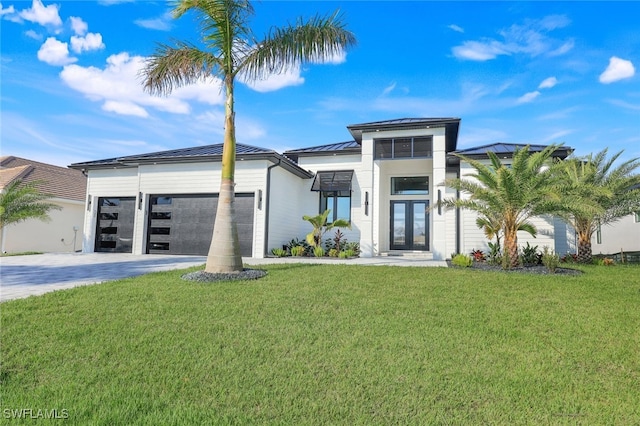 view of front of property with driveway, an attached garage, a standing seam roof, french doors, and a front yard