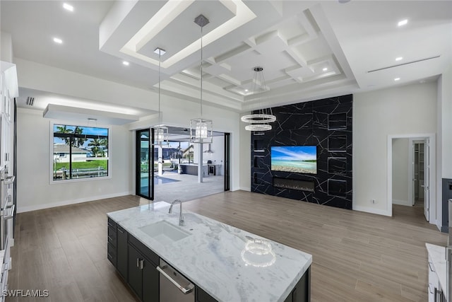 kitchen with open floor plan, white cabinetry, decorative light fixtures, and an island with sink