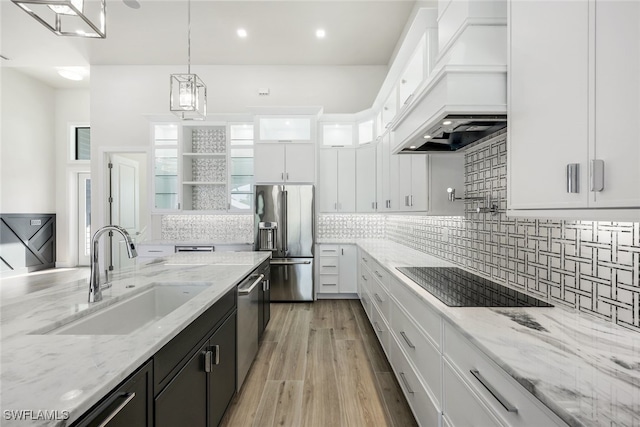 kitchen featuring white cabinets, glass insert cabinets, decorative light fixtures, stainless steel appliances, and a sink