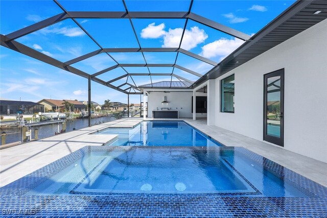 view of swimming pool with an in ground hot tub, a patio, a water view, and glass enclosure