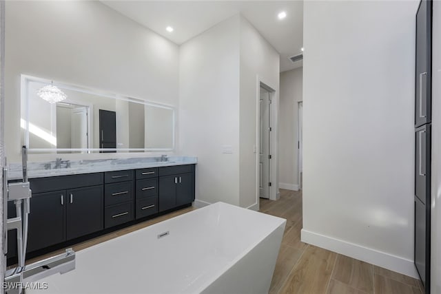 bathroom with a freestanding bath, double vanity, a sink, and visible vents