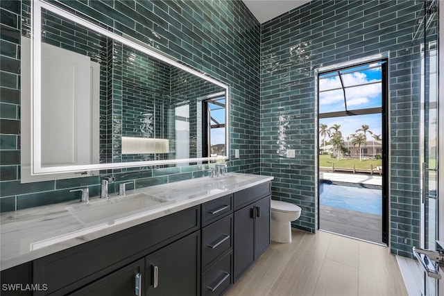 bathroom with a sink, tile walls, toilet, and double vanity