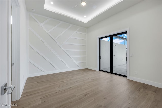 spare room featuring light wood-style flooring, built in shelves, baseboards, and a decorative wall