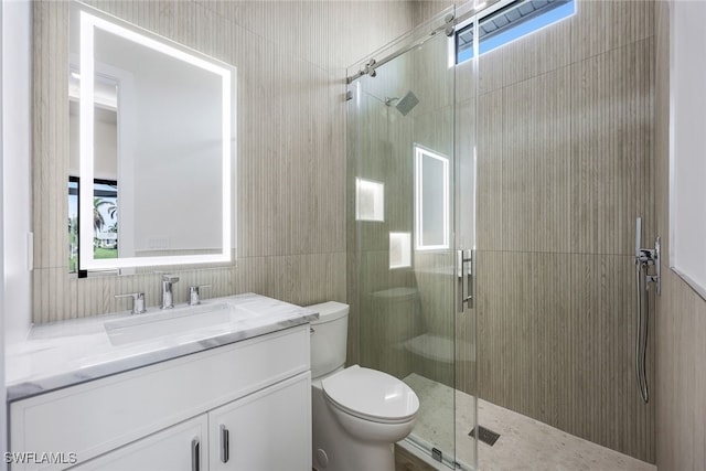 bathroom with vanity, toilet, walk in shower, and tile walls