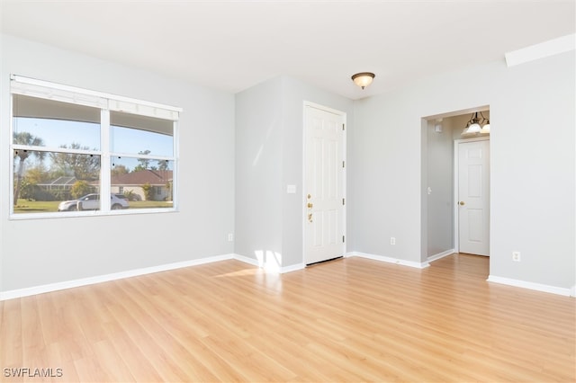 spare room featuring light wood-type flooring and a notable chandelier