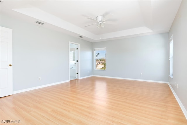 spare room featuring light hardwood / wood-style floors, a wealth of natural light, and a tray ceiling