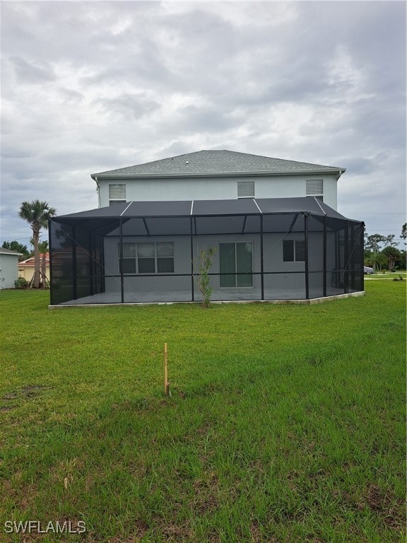 rear view of property featuring a lanai and a yard