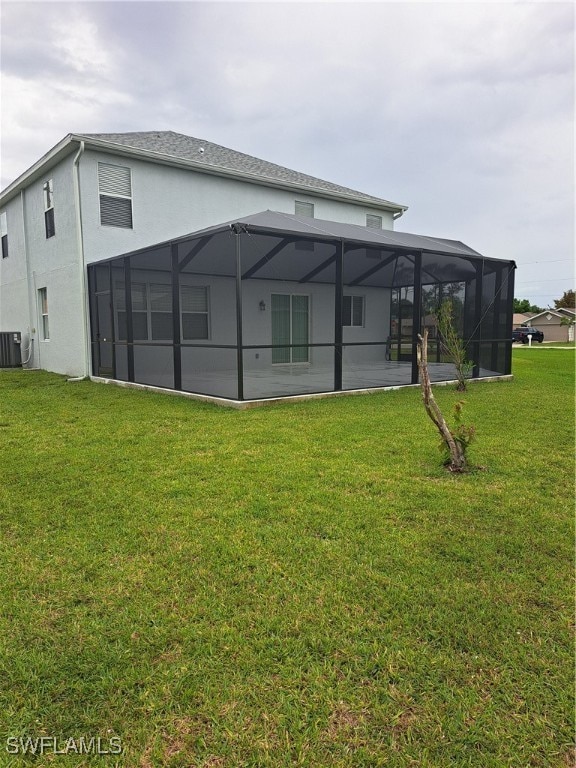 back of property with glass enclosure, a yard, and central AC