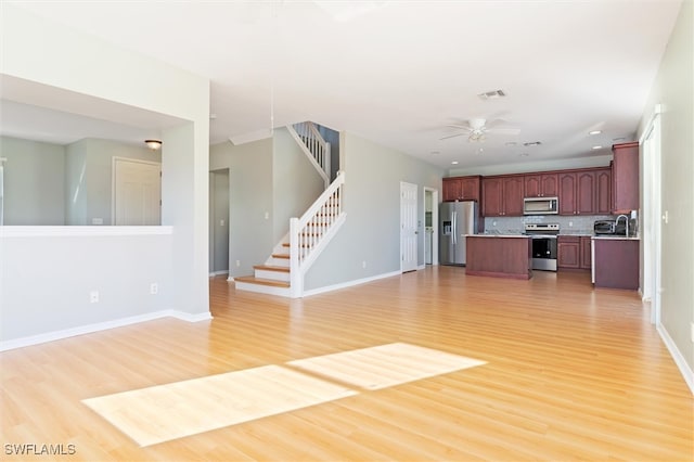 unfurnished living room featuring ceiling fan, sink, and hardwood / wood-style flooring