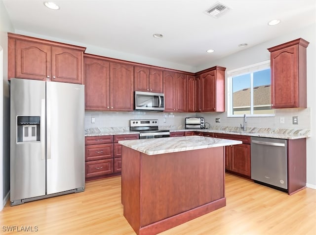 kitchen featuring a center island, sink, decorative backsplash, appliances with stainless steel finishes, and light hardwood / wood-style floors