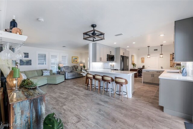 kitchen featuring sink, hanging light fixtures, a kitchen breakfast bar, black refrigerator, and a kitchen island