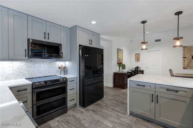 kitchen with gray cabinetry, hanging light fixtures, light hardwood / wood-style flooring, decorative backsplash, and appliances with stainless steel finishes