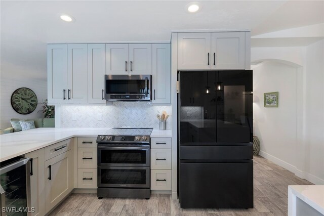 kitchen featuring decorative backsplash, appliances with stainless steel finishes, light wood-type flooring, beverage cooler, and white cabinetry