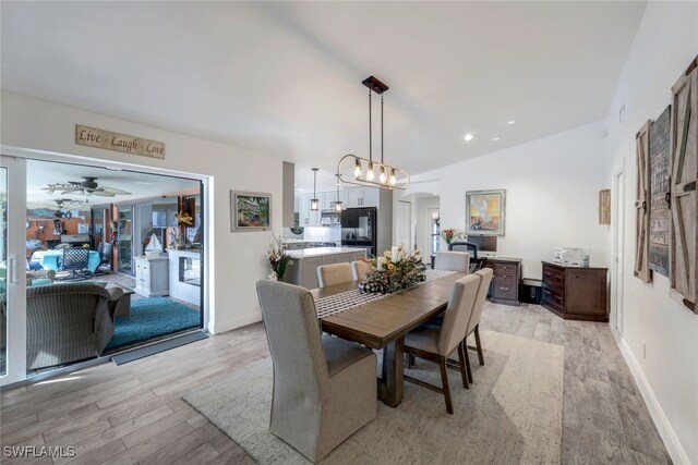 dining room featuring light wood-type flooring, vaulted ceiling, and ceiling fan