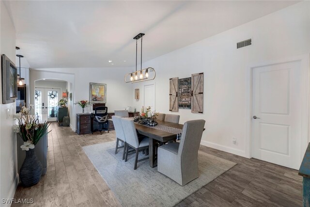 dining area with hardwood / wood-style flooring, vaulted ceiling, and french doors