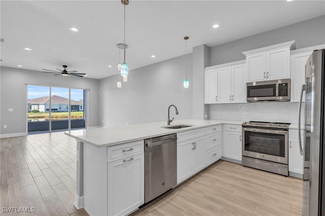 kitchen with kitchen peninsula, pendant lighting, sink, and stainless steel appliances