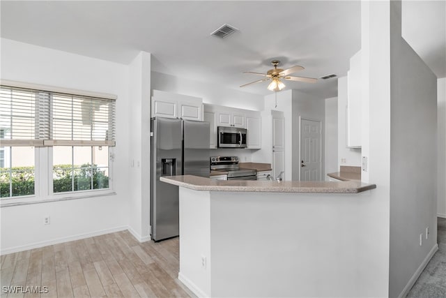 kitchen featuring appliances with stainless steel finishes, light wood-type flooring, kitchen peninsula, ceiling fan, and white cabinets