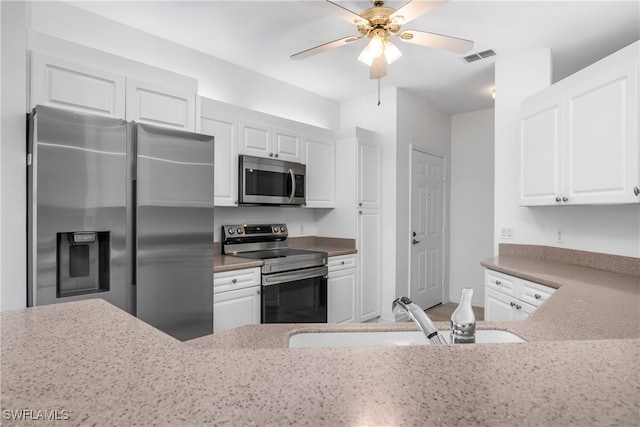 kitchen featuring sink, white cabinets, appliances with stainless steel finishes, light stone counters, and ceiling fan