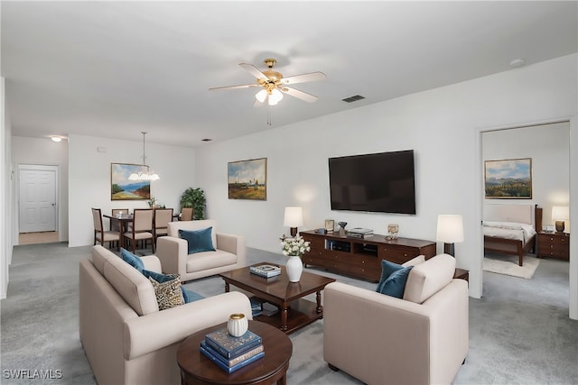 living room with light colored carpet and ceiling fan with notable chandelier