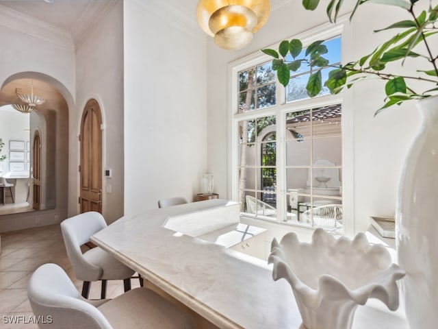 tiled dining area with crown molding and a notable chandelier