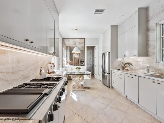 kitchen featuring backsplash, hanging light fixtures, white cabinetry, stainless steel refrigerator, and light tile patterned floors