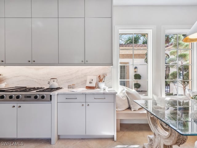 kitchen featuring stainless steel gas cooktop, tasteful backsplash, light stone counters, and light tile patterned floors