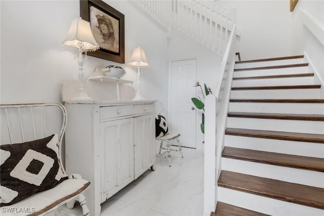 stairway featuring marble finish floor