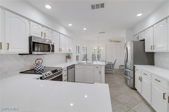 kitchen featuring stainless steel appliances, backsplash, light countertops, visible vents, and a peninsula