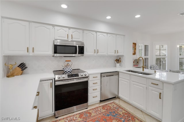 kitchen with kitchen peninsula, stainless steel appliances, backsplash, sink, and white cabinets